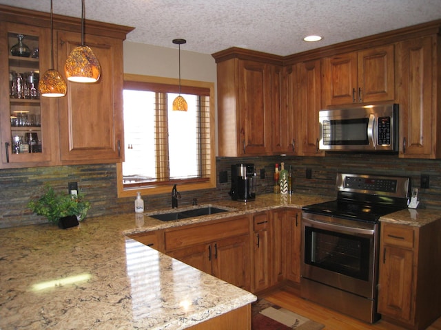 kitchen with hanging light fixtures, brown cabinets, appliances with stainless steel finishes, and a sink