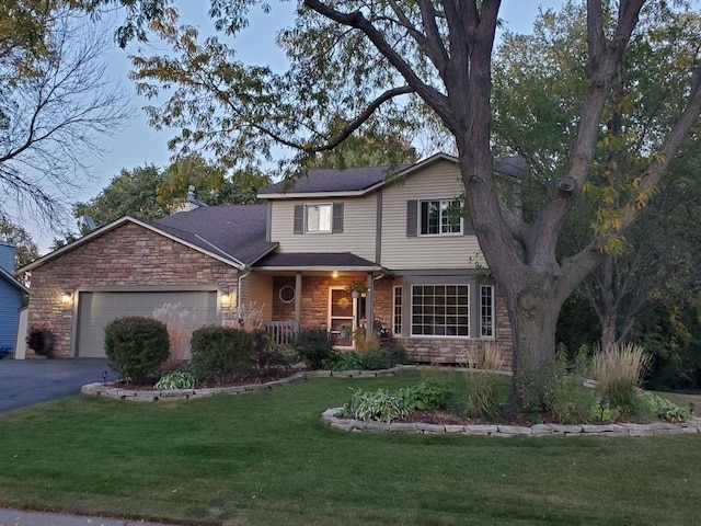 traditional-style home with stone siding, a front yard, an attached garage, and driveway