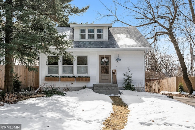 bungalow-style home with roof with shingles and fence