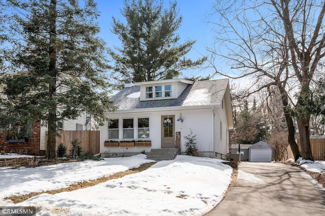 bungalow-style house with an outdoor structure, fence, a garage, and a shingled roof