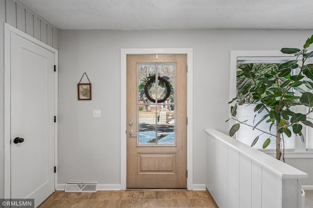 foyer entrance with visible vents, baseboards, and a textured ceiling