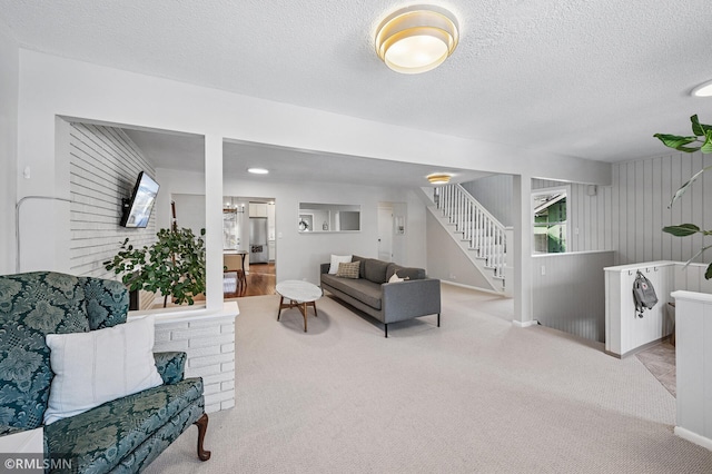 living area featuring stairway, carpet floors, and a textured ceiling