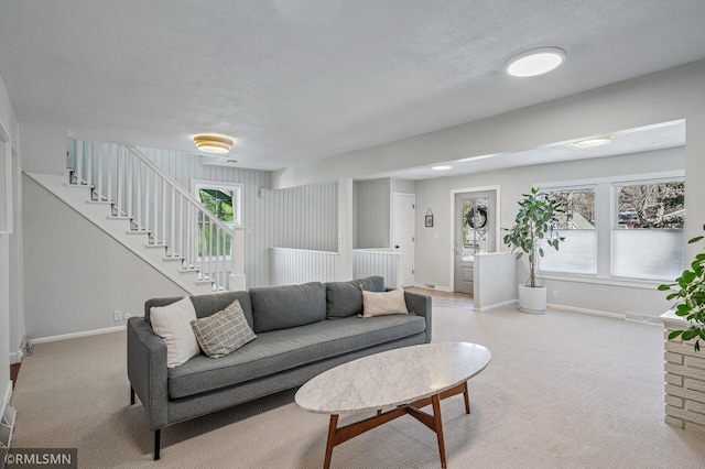 carpeted living area with visible vents, baseboards, a textured ceiling, and stairs