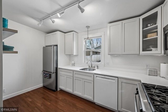 kitchen featuring a sink, dark wood-style floors, freestanding refrigerator, white dishwasher, and glass insert cabinets