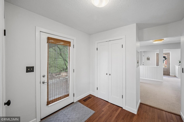 foyer entrance with wood finished floors, visible vents, and a textured ceiling