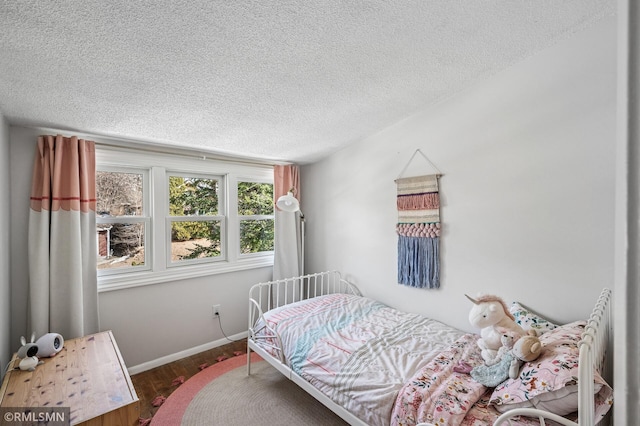 bedroom with baseboards, a textured ceiling, and wood finished floors