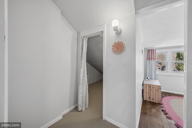 hallway with wood finished floors, baseboards, and a textured ceiling