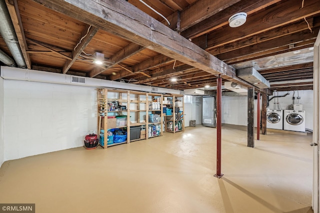 unfinished basement with visible vents, concrete block wall, and separate washer and dryer