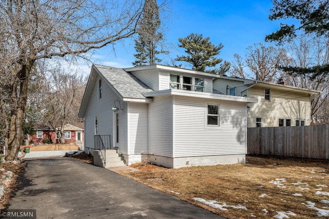 exterior space with fence and roof with shingles