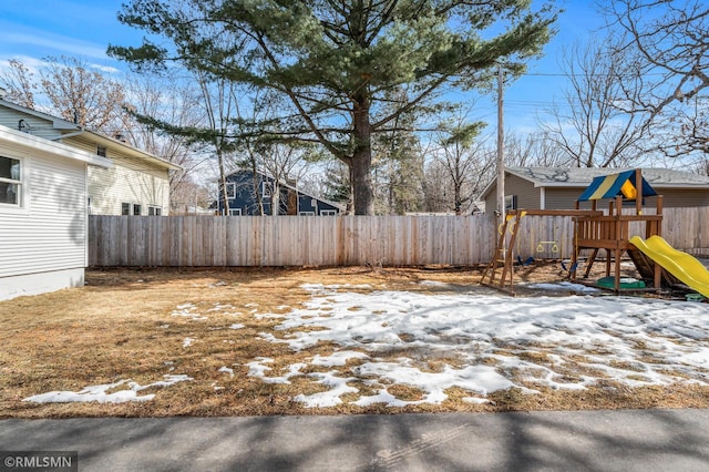 yard covered in snow featuring a playground and fence