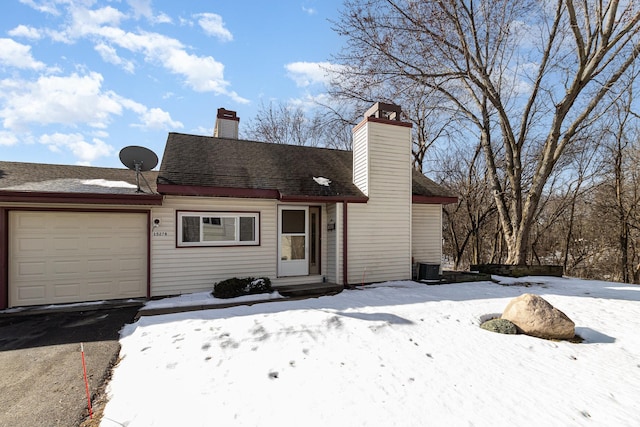 view of front of house with an attached garage, a chimney, and roof with shingles