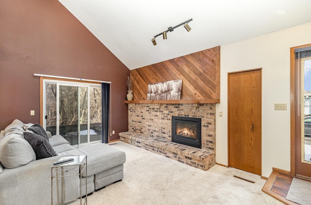 carpeted living area with visible vents, high vaulted ceiling, rail lighting, a fireplace, and baseboards