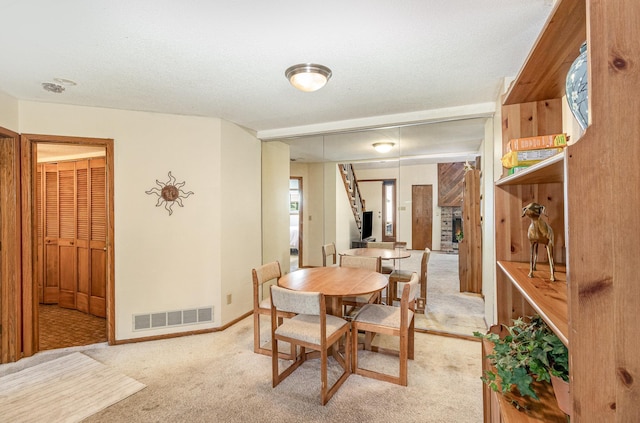 dining area featuring visible vents, light colored carpet, a textured ceiling, and baseboards