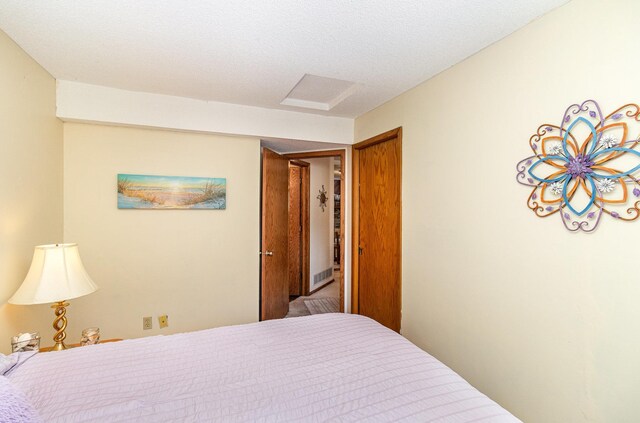 bedroom with a textured ceiling and attic access