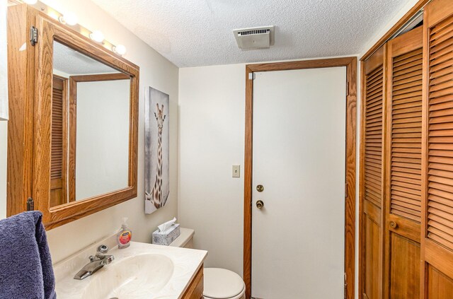 bathroom with a closet, a textured ceiling, and visible vents