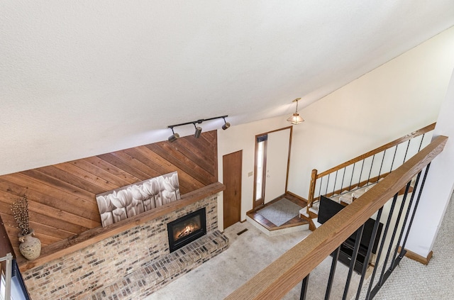 stairway with carpet flooring, rail lighting, baseboards, and a glass covered fireplace