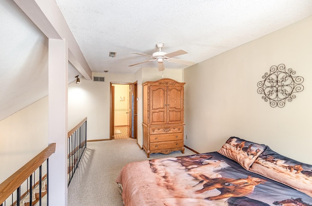 bedroom featuring visible vents, baseboards, ceiling fan, light colored carpet, and a textured ceiling