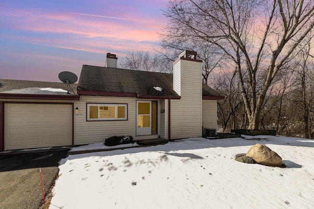 view of front of home featuring an attached garage, a chimney, and roof with shingles