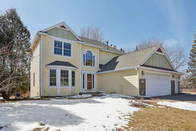 traditional-style house featuring roof with shingles, an attached garage, stone siding, aphalt driveway, and board and batten siding