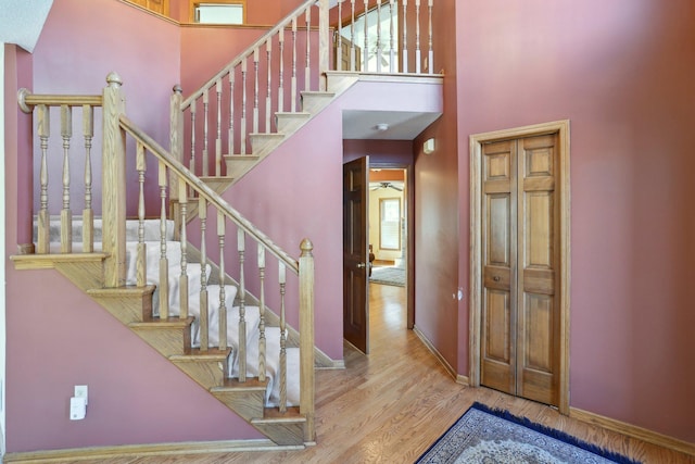 staircase with a high ceiling, baseboards, and wood finished floors