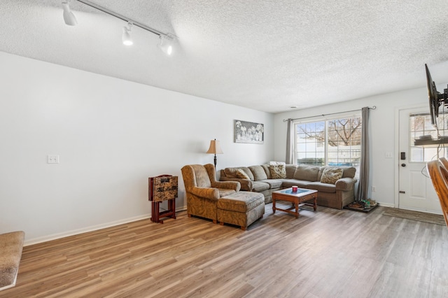 living area featuring baseboards, light wood-style floors, and a textured ceiling