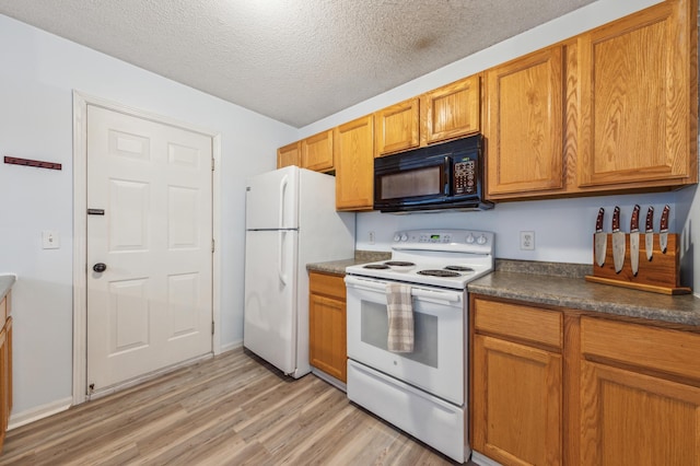 kitchen with a textured ceiling, dark countertops, white appliances, brown cabinetry, and light wood finished floors