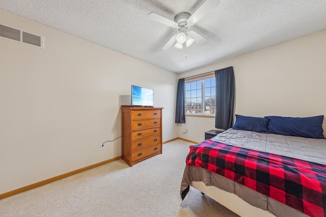 carpeted bedroom with visible vents, a textured ceiling, baseboards, and a ceiling fan