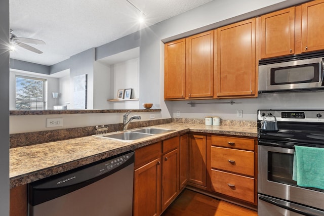 kitchen featuring stainless steel appliances, wood finished floors, a textured ceiling, a ceiling fan, and a sink