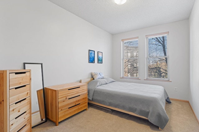 bedroom featuring baseboards, light colored carpet, and a textured ceiling