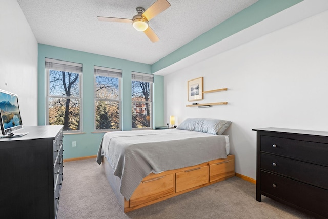 bedroom featuring light carpet, a ceiling fan, baseboards, and a textured ceiling