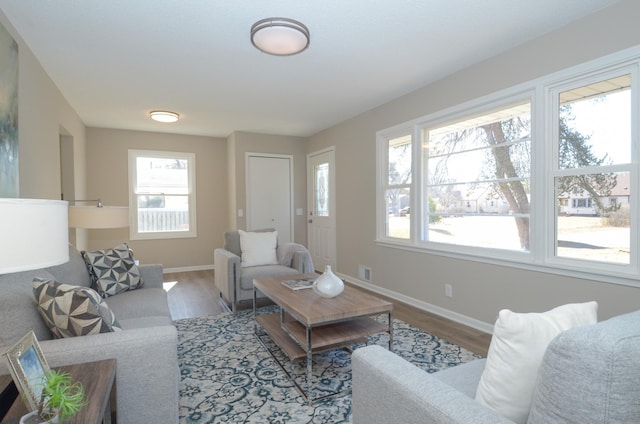 living room with wood finished floors, visible vents, and baseboards