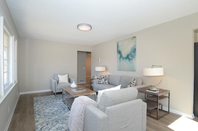 living area featuring visible vents, baseboards, and wood finished floors