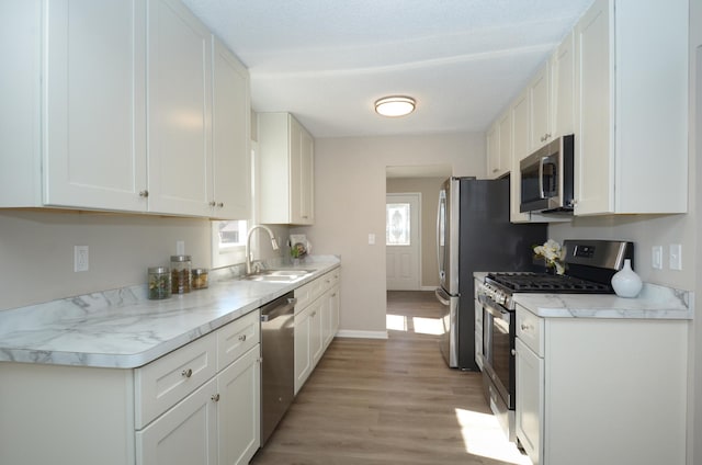 kitchen featuring white cabinets, appliances with stainless steel finishes, light countertops, and a sink