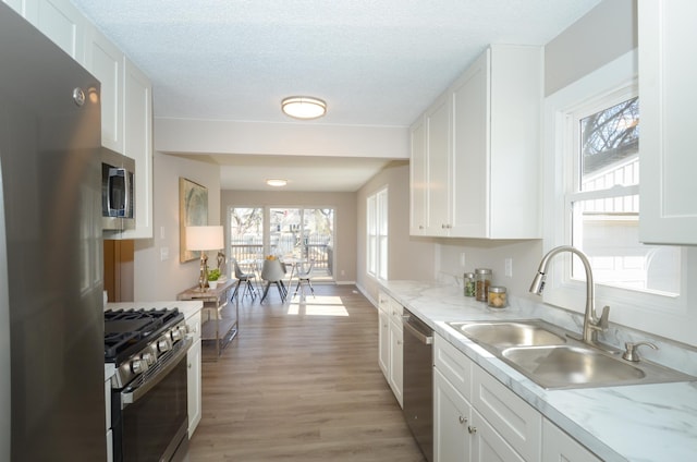 kitchen featuring a sink, light wood-type flooring, appliances with stainless steel finishes, and white cabinetry