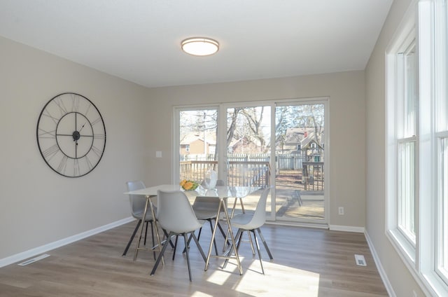 dining area featuring visible vents, baseboards, and wood finished floors