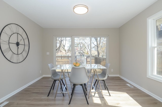 dining room featuring visible vents, baseboards, and light wood finished floors