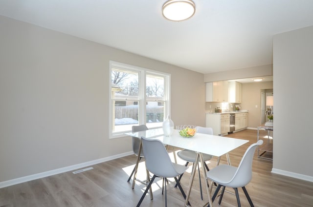 dining space with baseboards and light wood-style floors