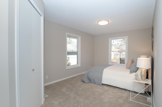 carpeted bedroom with multiple windows, baseboards, and a closet