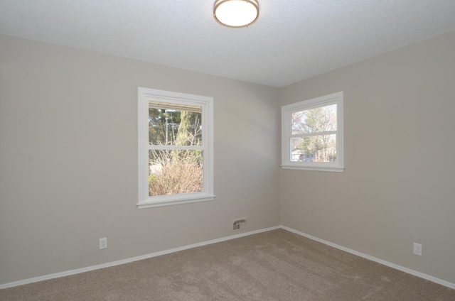 unfurnished room with a textured ceiling, baseboards, and carpet floors