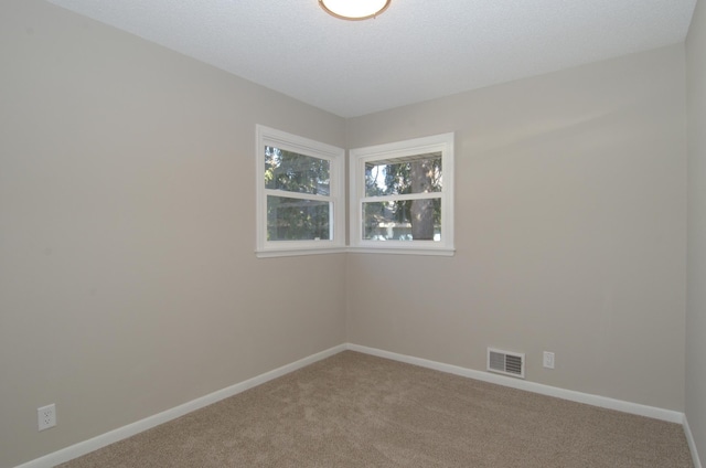 carpeted spare room featuring baseboards, visible vents, and a textured ceiling