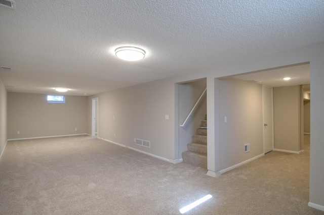 below grade area with visible vents, carpet floors, baseboards, and stairs