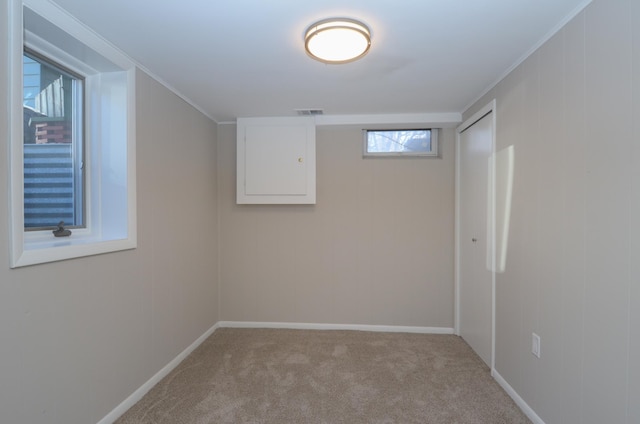 carpeted empty room featuring visible vents, baseboards, and crown molding