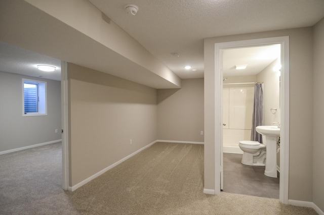 below grade area with baseboards, carpet, and a textured ceiling