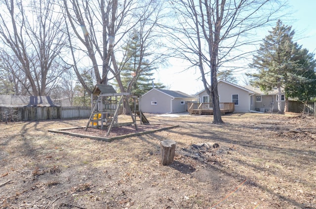 view of yard with a wooden deck, a playground, and fence