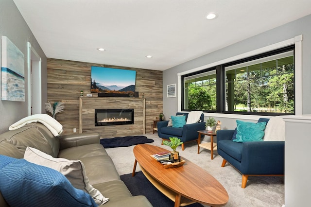 carpeted living room with an accent wall, wooden walls, recessed lighting, and a tile fireplace