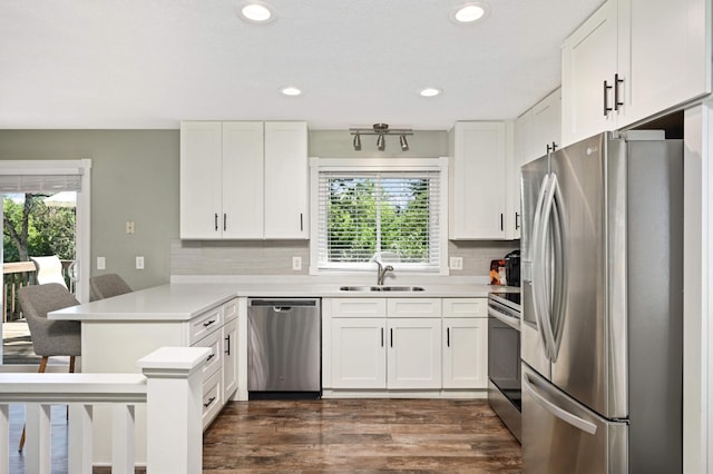 kitchen with a peninsula, a sink, light countertops, white cabinets, and appliances with stainless steel finishes