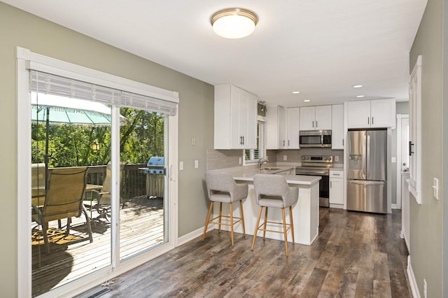 kitchen featuring white cabinets, a peninsula, stainless steel appliances, and a sink