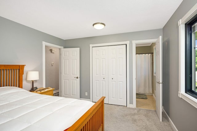 bedroom with a closet, light colored carpet, and baseboards