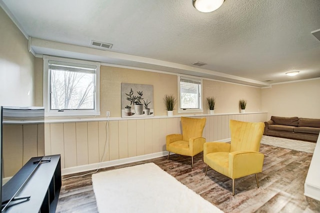 sitting room featuring visible vents, a textured ceiling, and wood finished floors