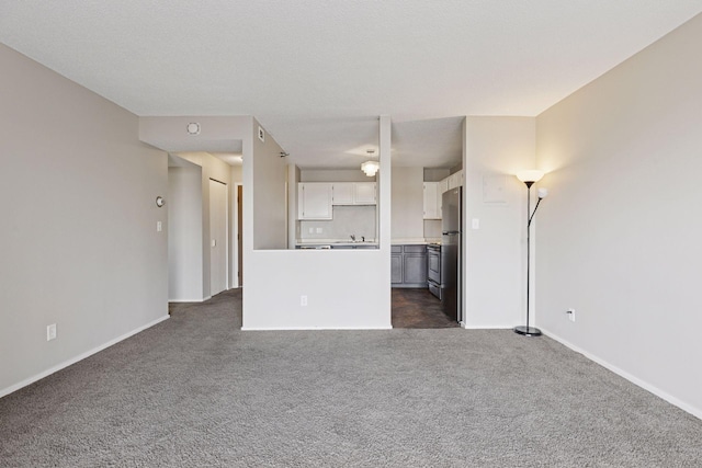 unfurnished living room featuring dark colored carpet and baseboards